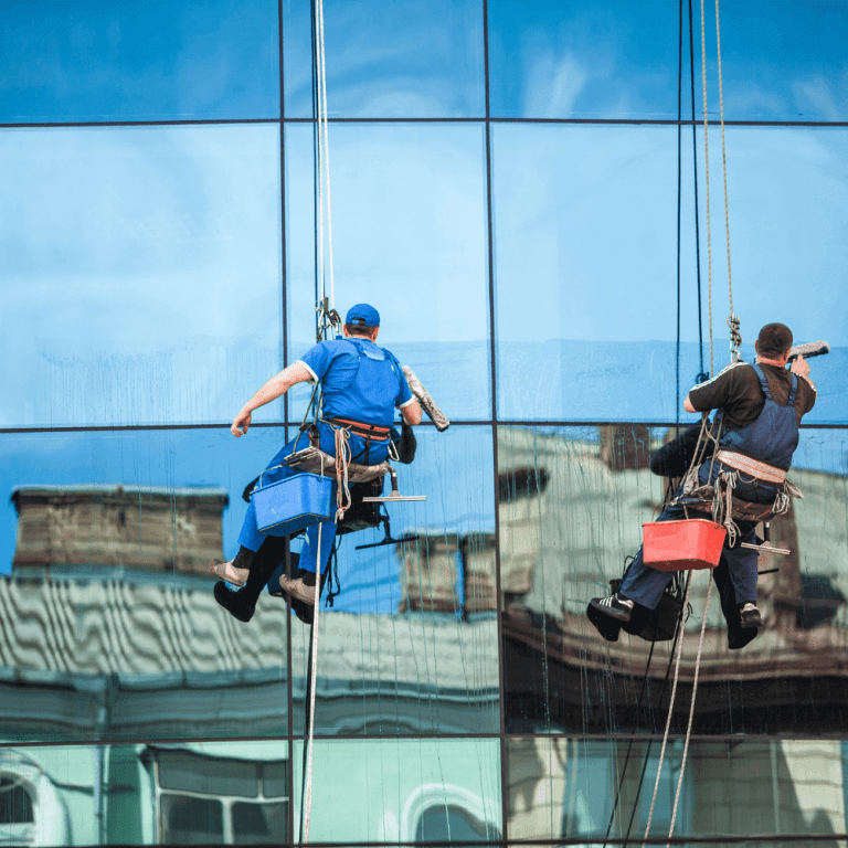 A worker cleaning tall commercial building windows
