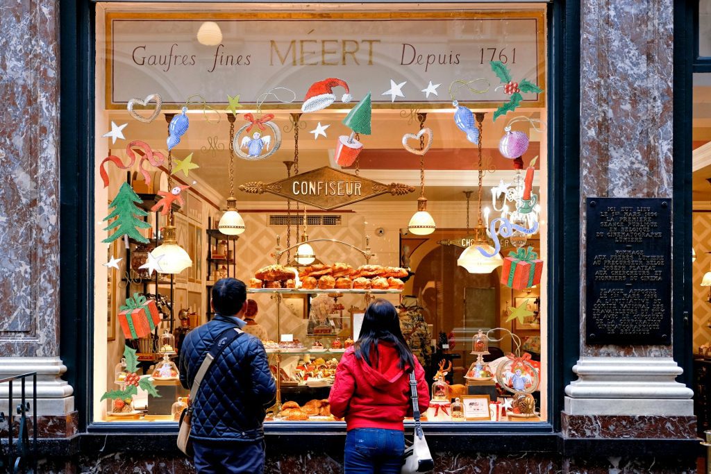 A man and woman are looking into a storefront window