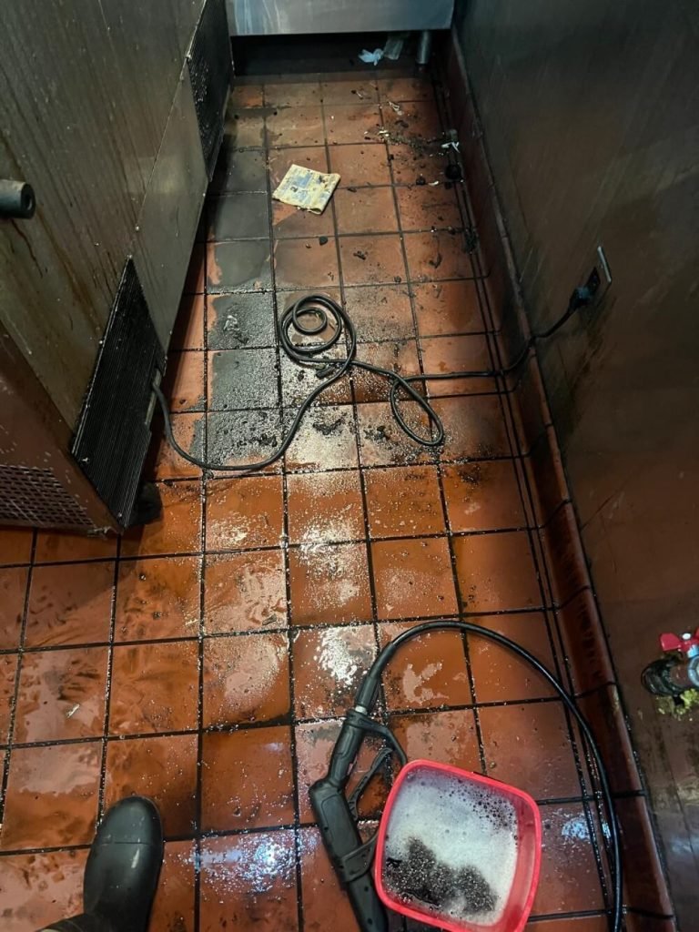Dirty tile and grout floor coated with black grime before cleaning