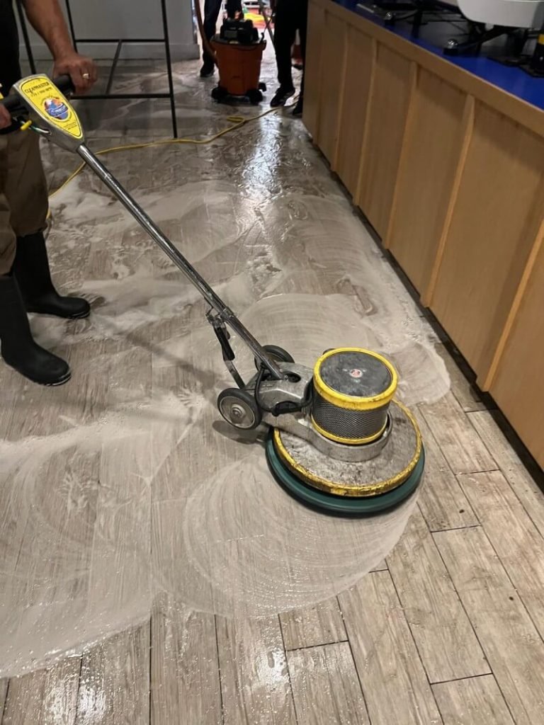 A professional cleaner mopping the floor in a commercial kitchen