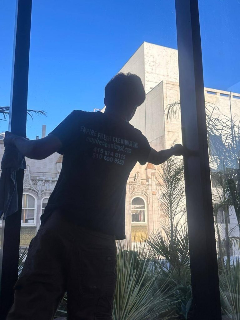 A window cleaner squeegees an interior window looking out onto historic San Francisco