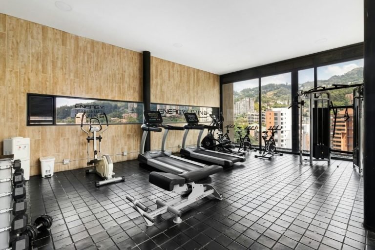 A gym exercise room with large windows and tiled floors.