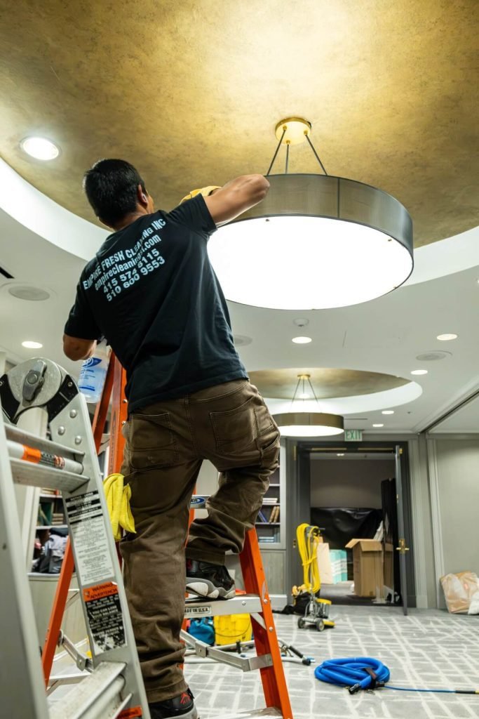 A man cleaning a lighting fixture in a theatre lobby