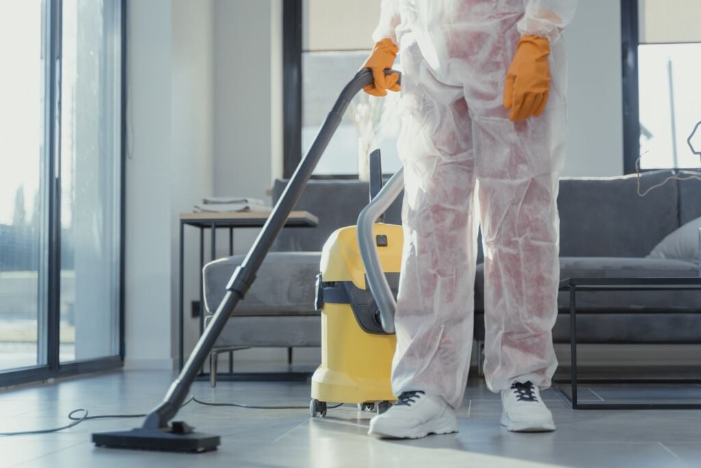A professional cleaner with orange gloves steam cleaning a gray tile floor